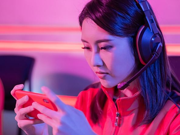 young woman gaming on mobile phone while wearing headphones